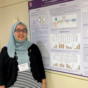 Uzma Hasan standing next to her research poster