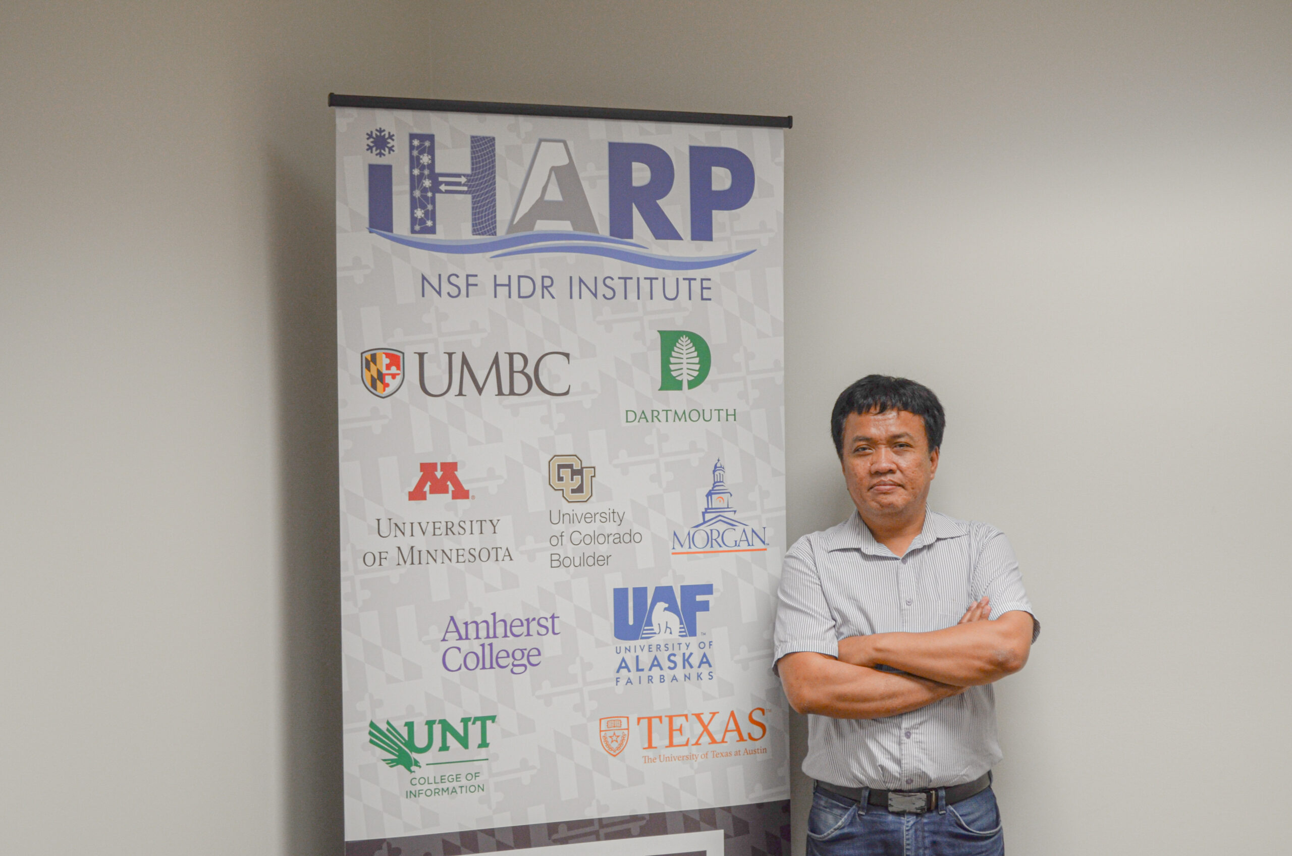 Bayu Adhi Tama standing in front of the iHARP banner