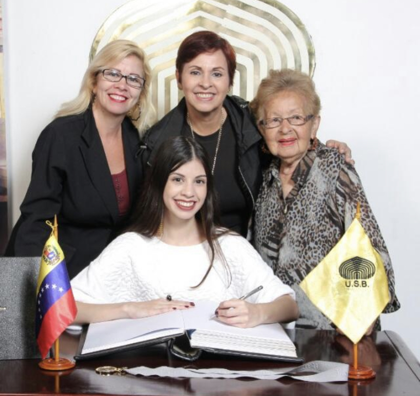 four women standing behind a desk during a ceremony