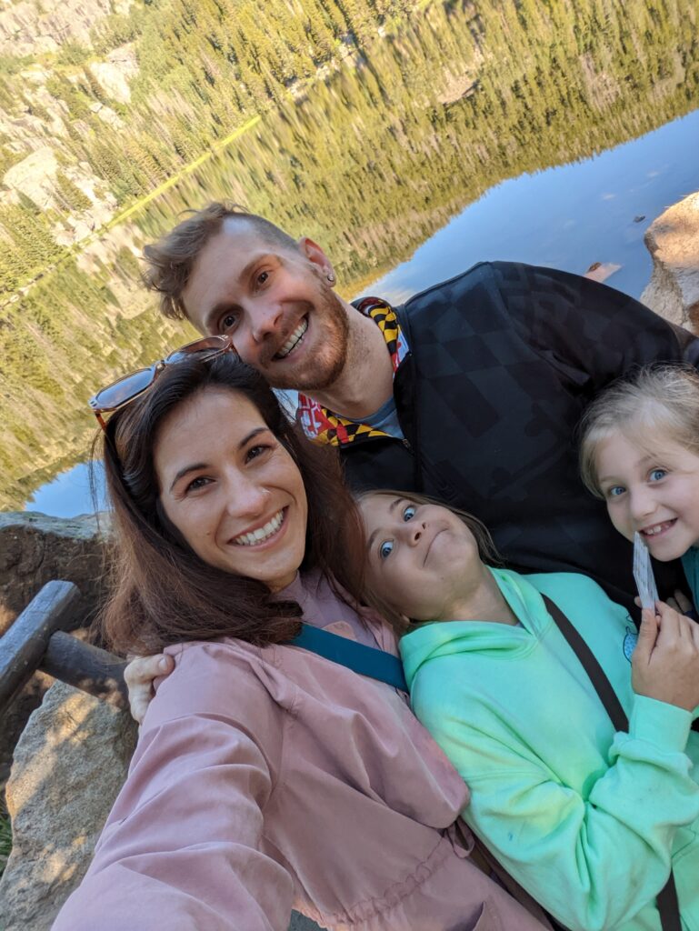 family posing for photo outside near water