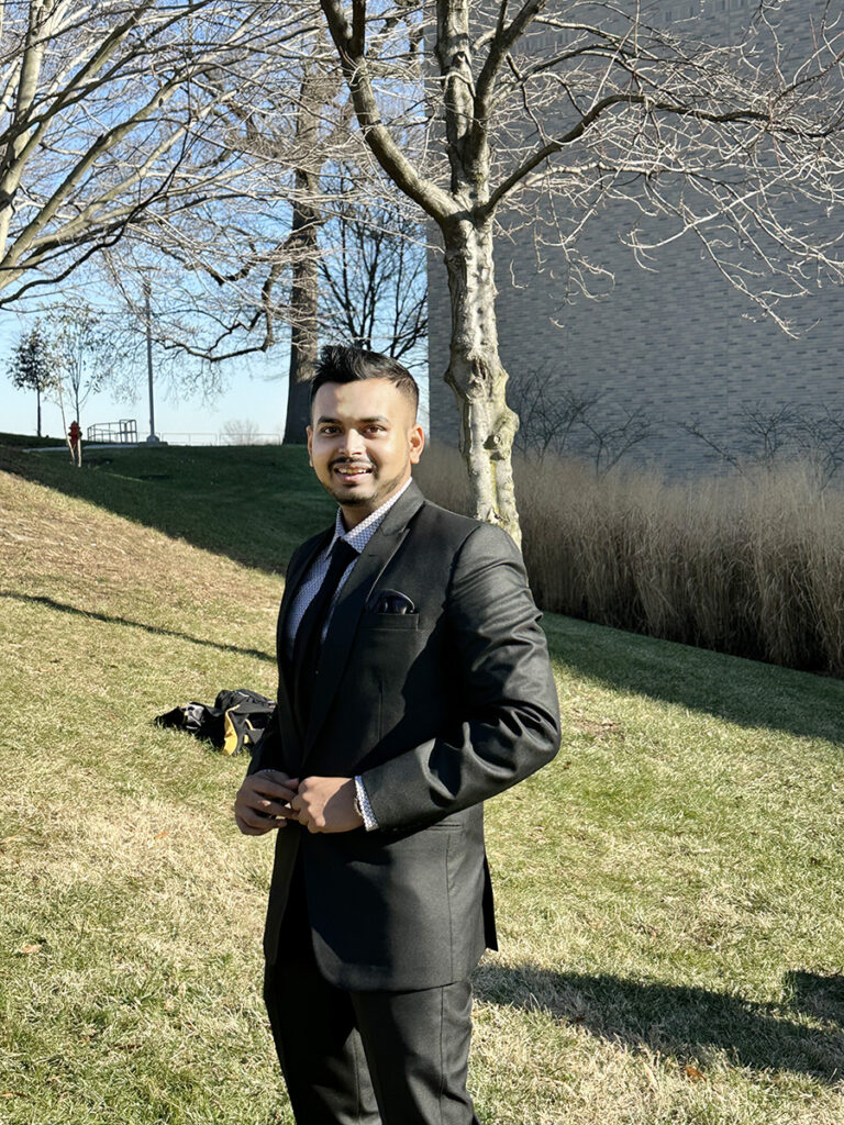 person standing outside on a sunny day while wearing a suit