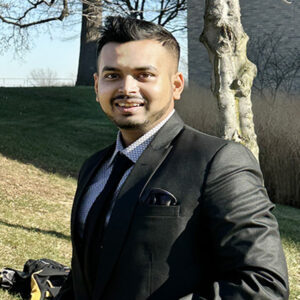 Mihir Patel standing in front of a tree in a suit