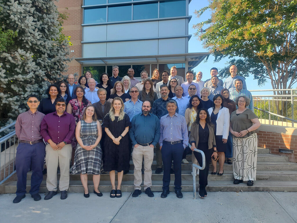 IS faculty group photo, standing on the stairs in from of the building