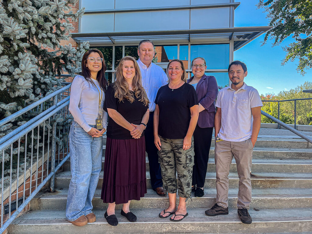 IS staff photo, standing outside on stairs in front of the building