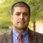 Ravi Kuber headshot, standing outside on campus